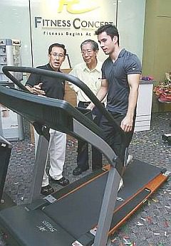 Fit for all: Au Yong (left) explaining characteristics of a Fitness Concept treadmill to Olympic Council of Malaysia secretary Datuk Sieh Kok Chi as Fitness Concept ambassador Kevin Zahri demonstrates on the treadmill.